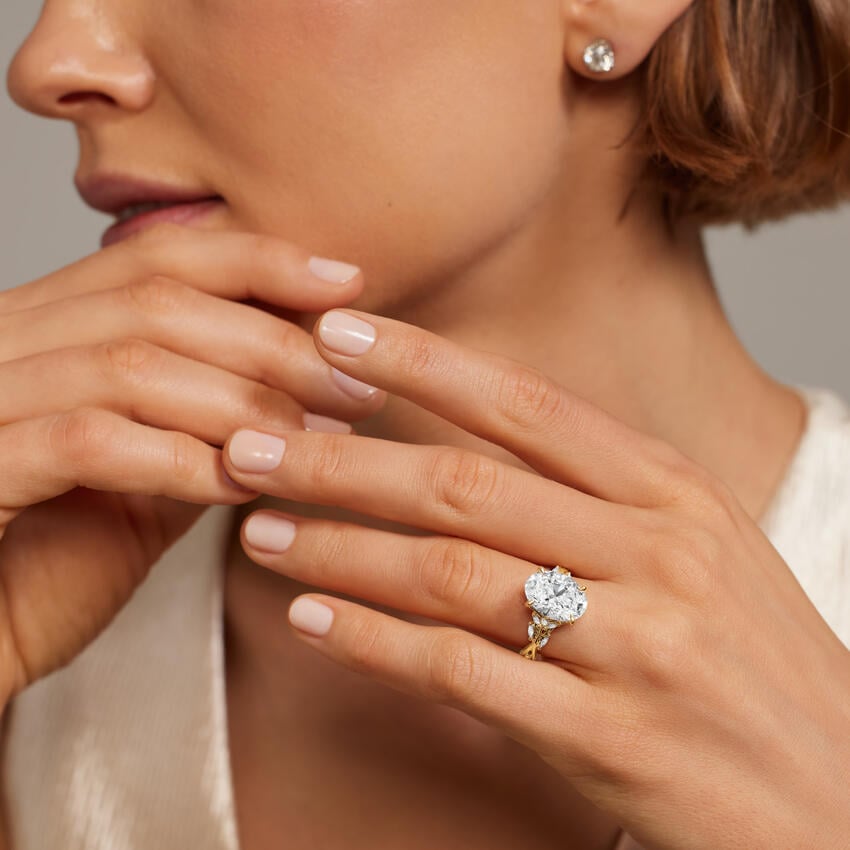 Close-up of a woman's hand wearing a diamond ring with a neutral background