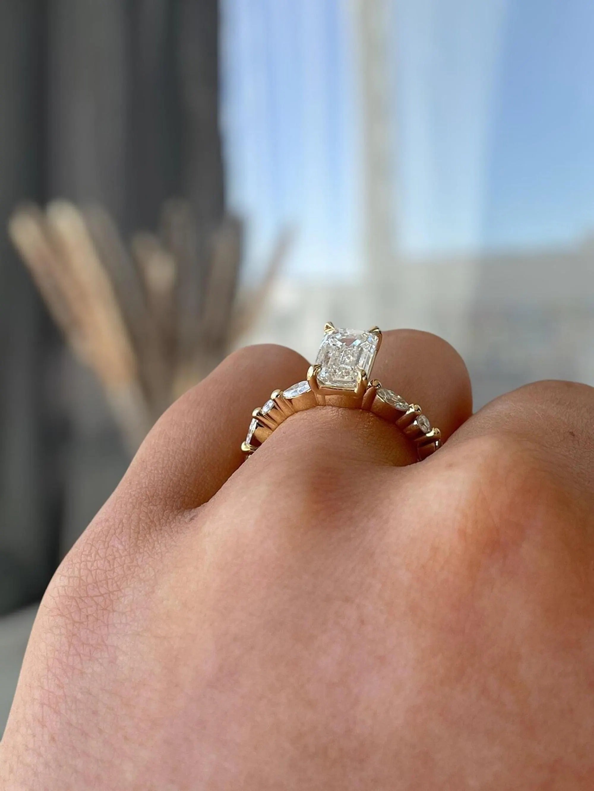 Gold ring with a diamond on a person's finger against a blurred background