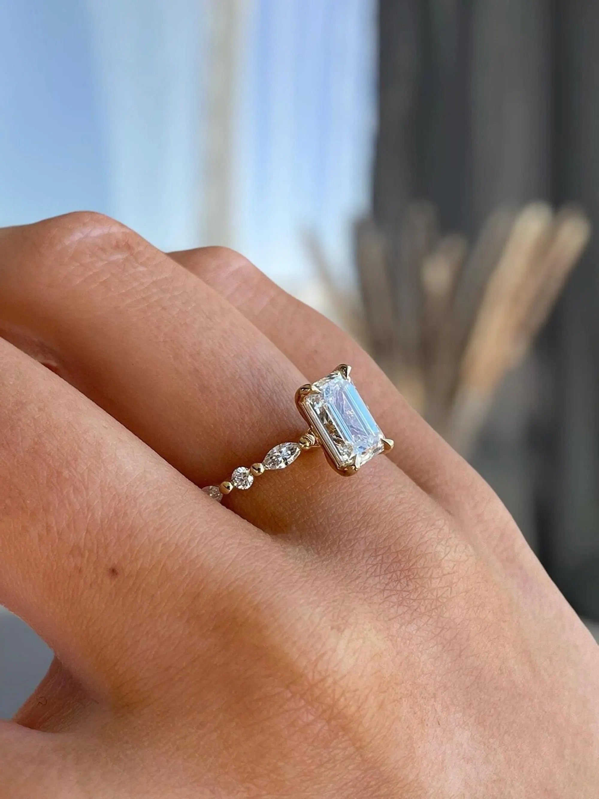 Gold ring with a large diamond on a person's finger against a blurred background