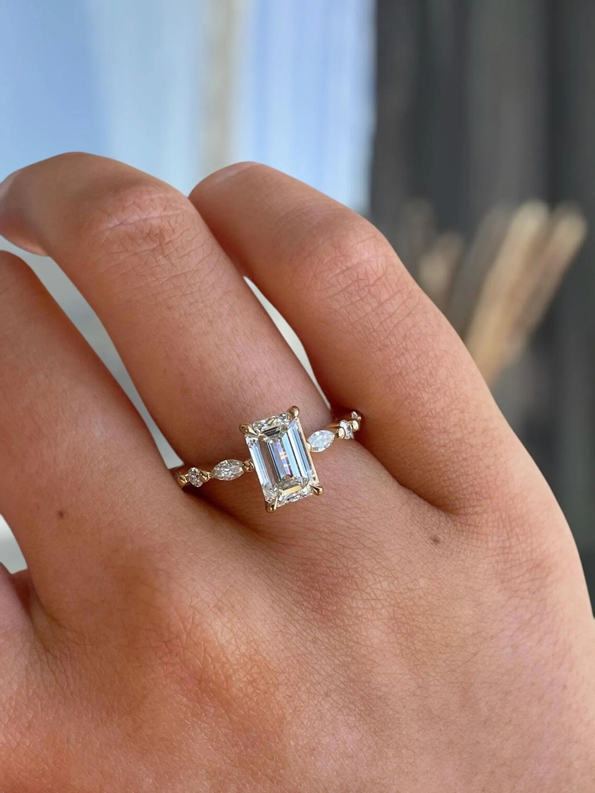 Ring with a large diamond on a person's finger against a blurred background
