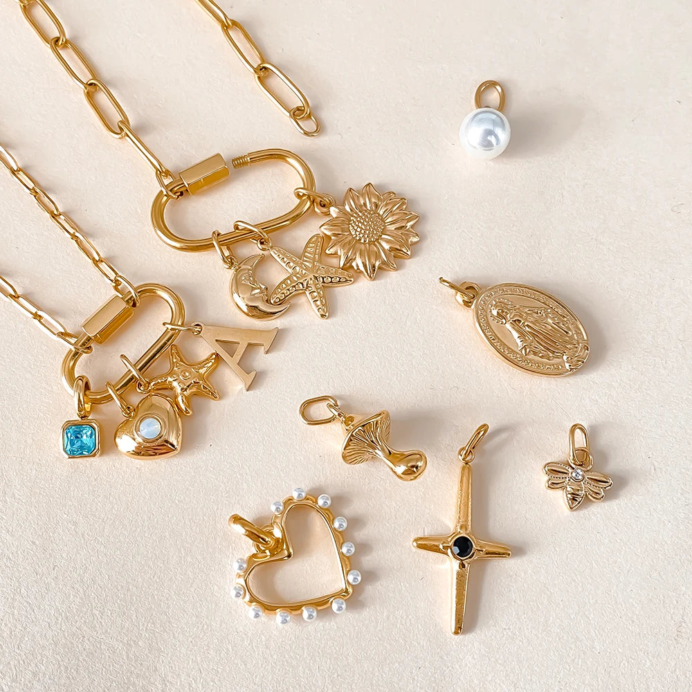 Collection of gold jewelry charms on a light beige background